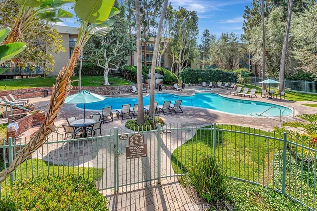 a view of a patio with a table and chairs under an umbrella with a small yard