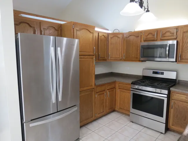 a kitchen with stainless steel appliances granite countertop a refrigerator and a stove top oven