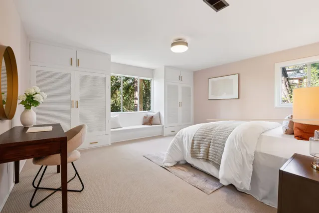 a bedroom with a bed table chair and a window