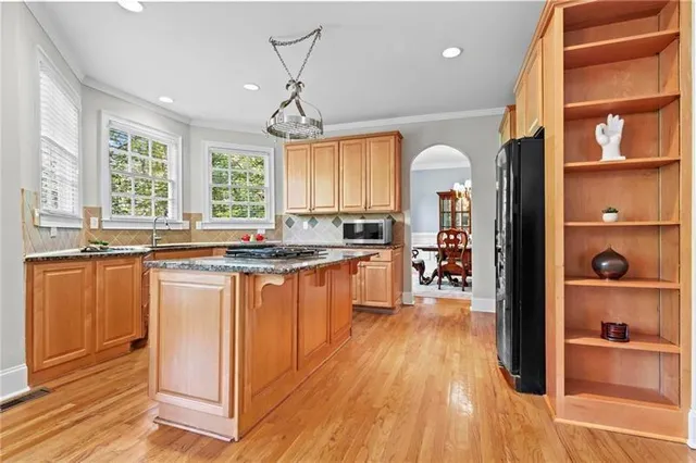 a kitchen with stainless steel appliances granite countertop a refrigerator a sink dishwasher a stove and white countertops with wooden floor