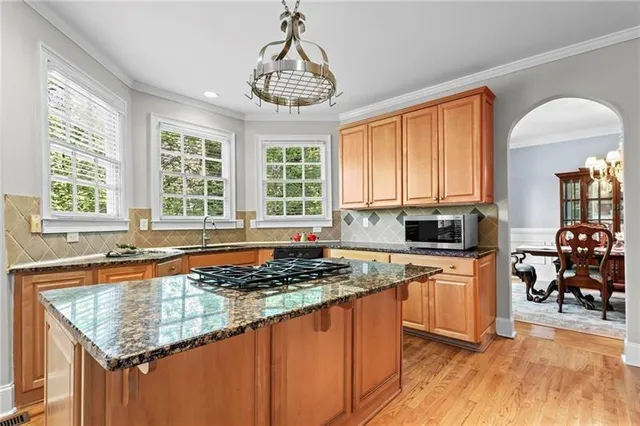 a kitchen with stainless steel appliances granite countertop a stove top oven a sink dishwasher and cabinets with wooden floor