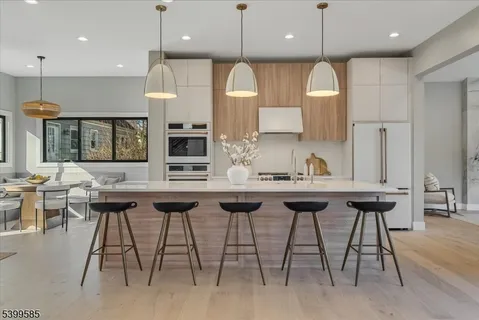 a kitchen with stainless steel appliances granite countertop a kitchen island a stove a cabinets a sink a chair and a refrigerator