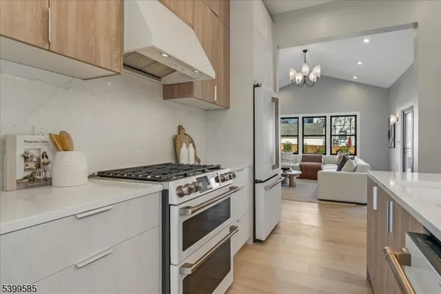 a kitchen with stainless steel appliances granite countertop a stove and white cabinets with wooden floor