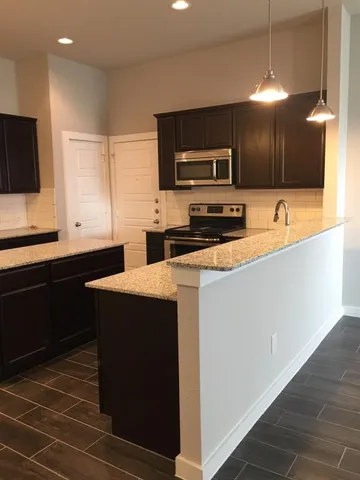 a kitchen with stainless steel appliances a sink a stove a microwave a counter top space and cabinets