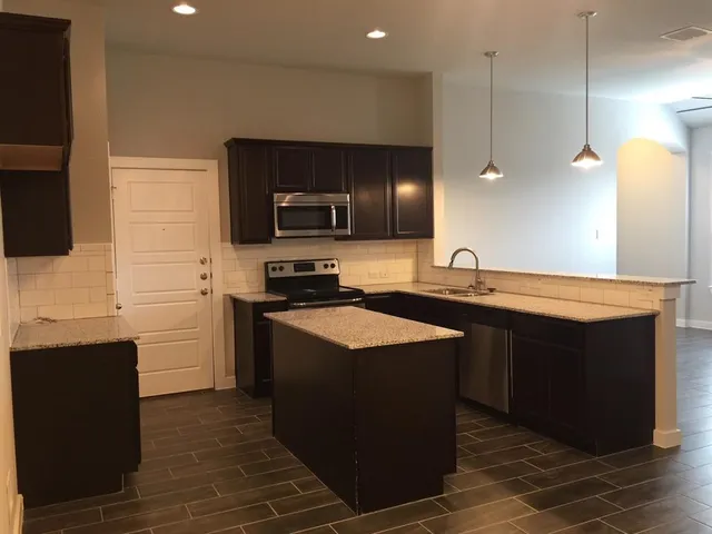 a kitchen with stainless steel appliances granite countertop a sink a stove and a wooden floors
