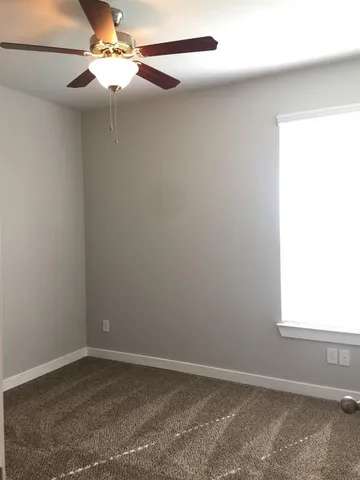 an empty room with a window and a fan