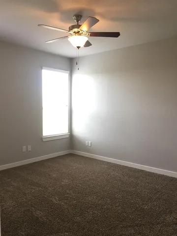 an empty room with a window and a ceiling fan