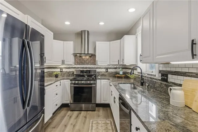 a kitchen with stainless steel appliances granite countertop a stove top oven a sink and a refrigerator