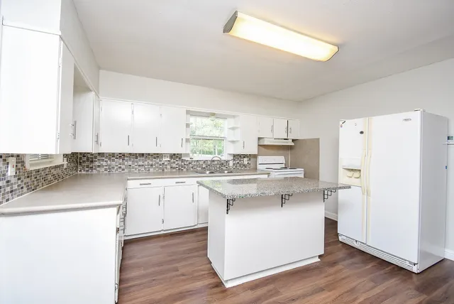 a kitchen with a sink a refrigerator and white cabinets