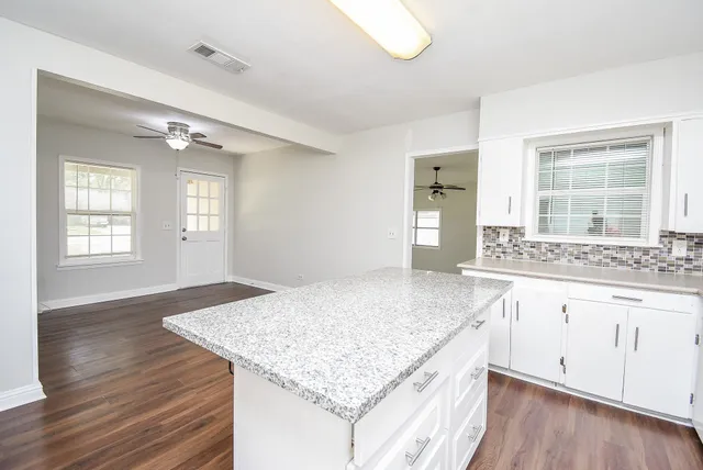 a kitchen with granite countertop kitchen island a sink stove and wooden floor