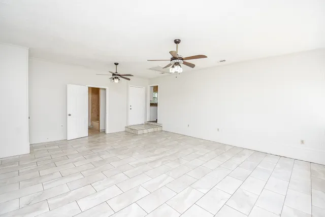 an empty room with white walls and ceiling fan