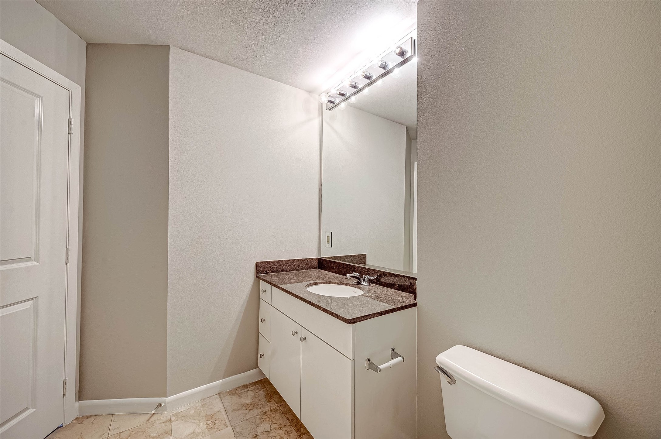 3505 Sage Road, Unit 2106 Houston, TX 77056 - Photo 17 of 31 This bathroom features a sleek, modern design with a single vanity, granite countertop, large mirror, and neutral tile flooring.
