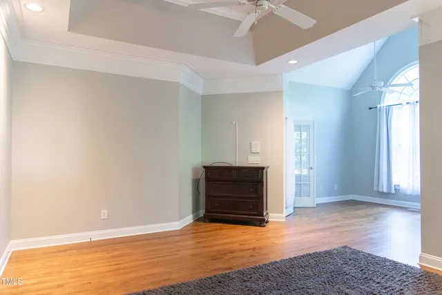 a view of empty room with wooden floor and fan