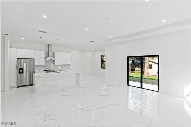 a large white kitchen with kitchen island granite countertop lots of white stainless steel appliances