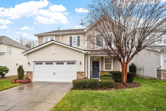 a view of a yard in front of a house with plants and large tree