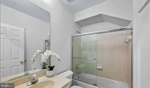 a bathroom with a granite countertop shower sink vanity and toilet