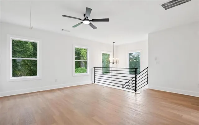 an empty room with wooden floor fan and windows
