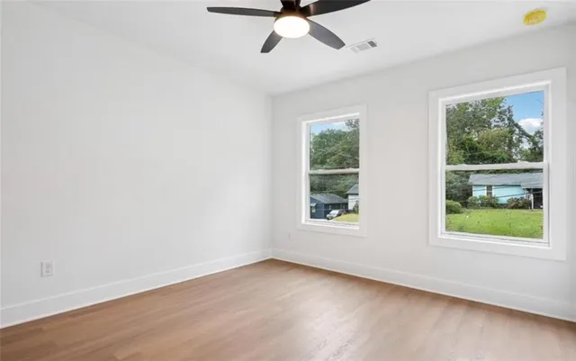an empty room with wooden floor and windows