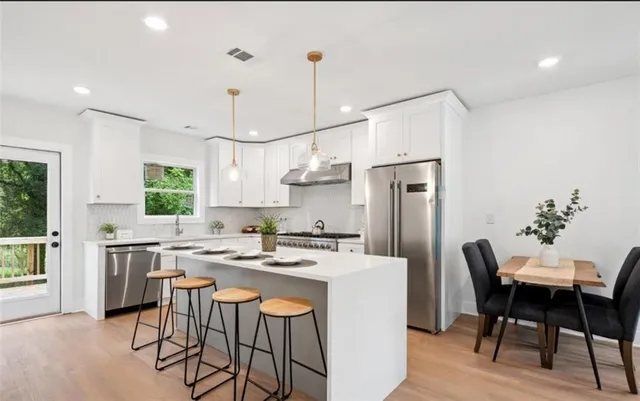 a kitchen with stainless steel appliances granite countertop a dining table chairs stove refrigerator and cabinets