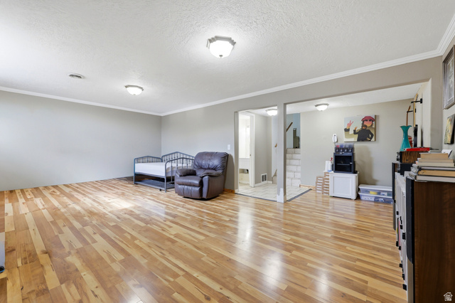 1486 3rd Street Ogden, UT 84404 - Photo 15 of 26 Spacious room featuring wood-finish flooring, light gray wall paint, white crown molding, and two ceiling-mounted light fixtures