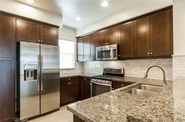 a kitchen with stainless steel appliances granite countertop a sink refrigerator and microwave