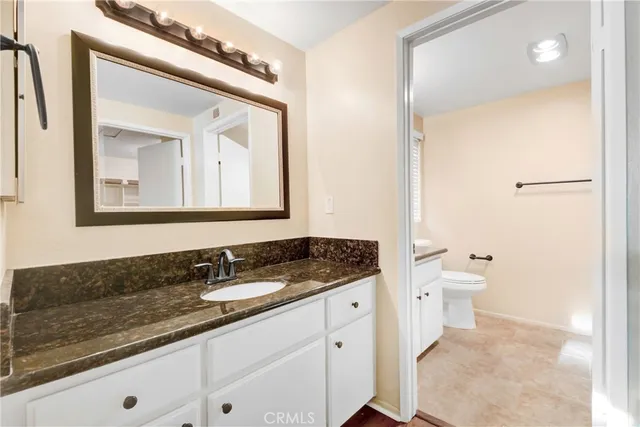 a bathroom with a granite countertop sink a mirror and a toilet