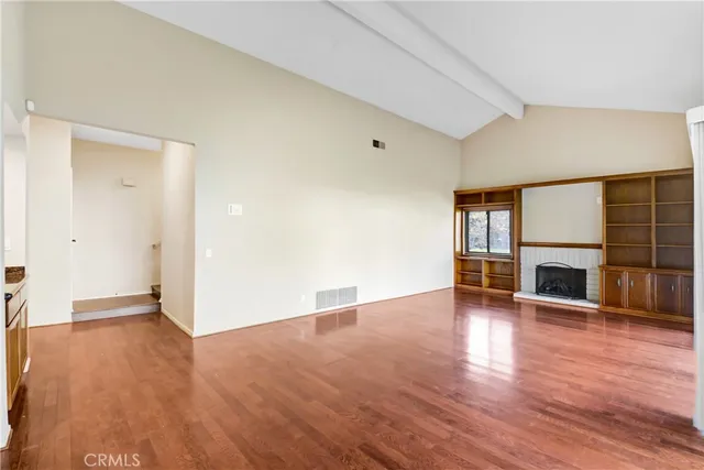 an empty room with wooden floor and fireplace
