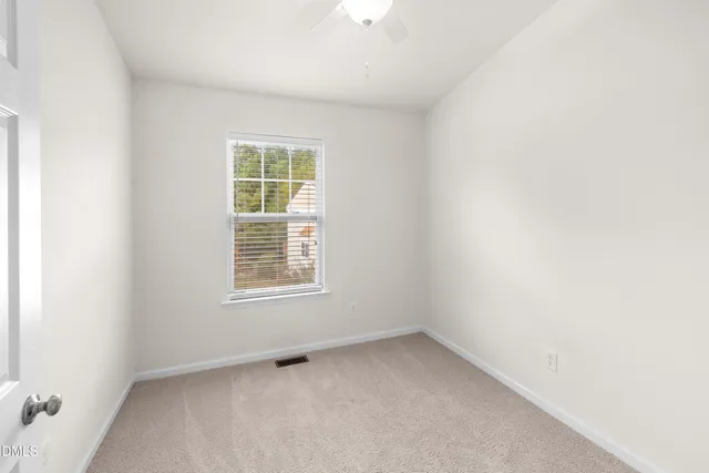 an empty room with a ceiling fan and a window