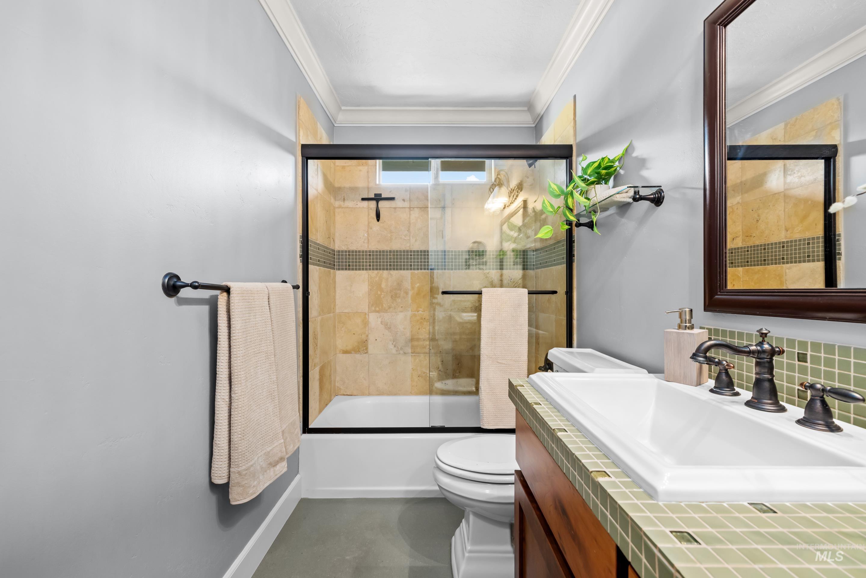 1862 West Ridenbaugh Street Boise, ID 83702 - Photo 35 of 40 Shower with glass enclosure, vanity with integrated sink, tile countertop, and dark wood-finish cabinet