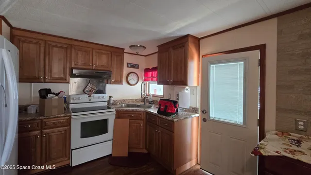 a kitchen with stainless steel appliances granite countertop a stove top oven a sink dishwasher and a refrigerator with wooden cabinets