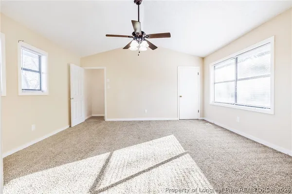 an empty room with windows and fan