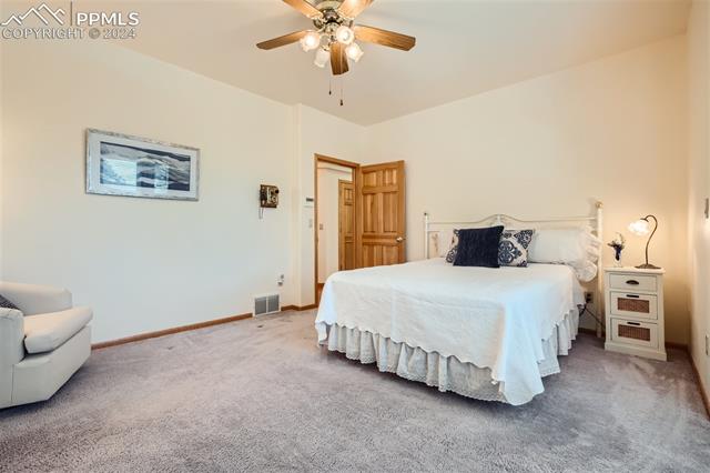 3715 Range View Road Monument, CO 80132 - Photo 16 of 49 Bedroom featuring ensuite bath, ceiling fan, and light carpet.