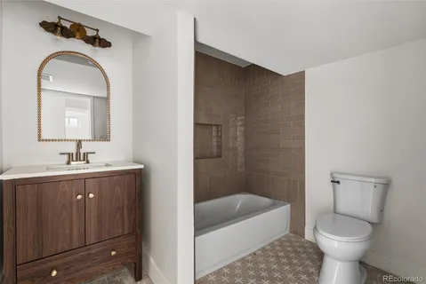 a bathroom with a toilet a sink a mirror a bathtub and vanity