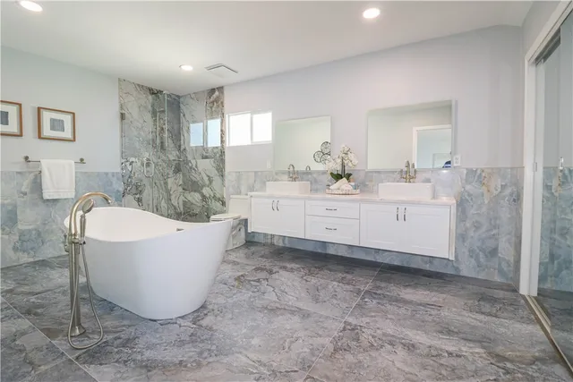a spacious bathroom with a tub sink and mirror
