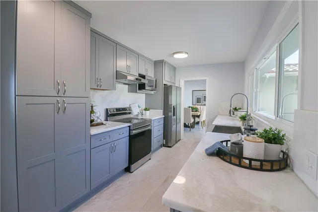 a kitchen with kitchen island granite countertop a sink cabinets and stainless steel appliances