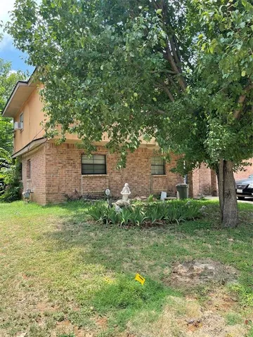 a backyard of a house with plants and large tree
