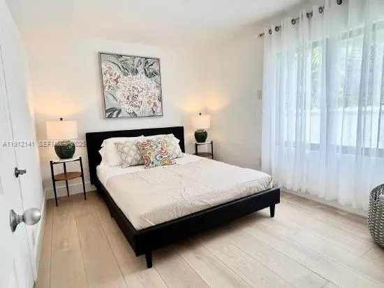 a bedroom with a bed painting on wall and a large window