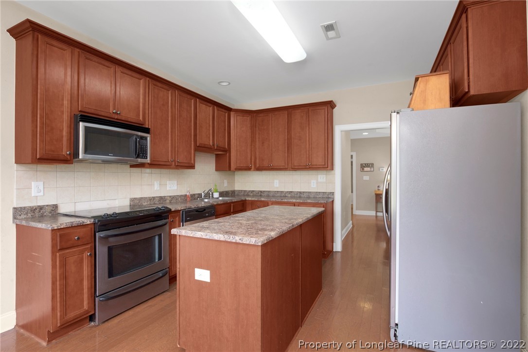 515 Booth Pond Road Raeford, NC 28376 - Photo 14 of 39 a kitchen with stainless steel appliances granite countertop wooden cabinets a stove top oven a sink and dishwasher