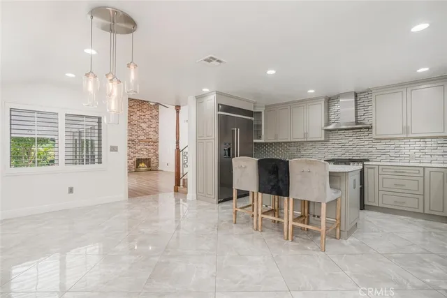 a large white kitchen with granite countertop lots of white cabinets and stainless steel appliances