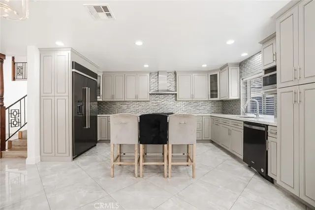 a large kitchen with cabinets chairs and stainless steel appliances