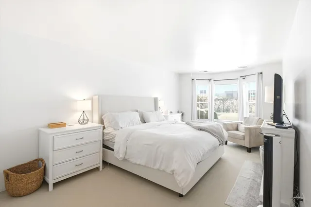 a bedroom with a bed and large windows