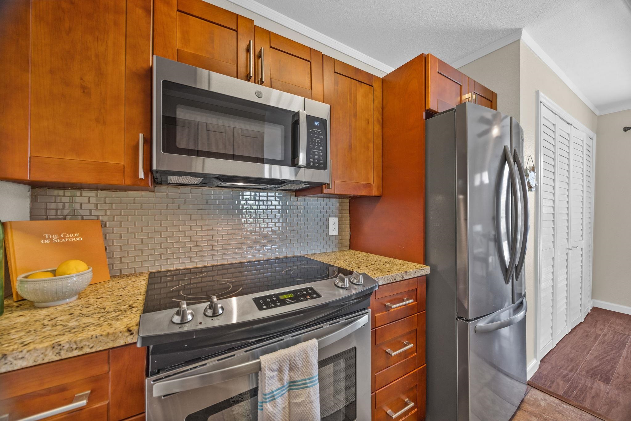 140 Uwapo Road, Unit 53201 Kihei, HI 96753 - Photo 13 of 28 a kitchen with stainless steel appliances granite countertop a stove microwave and refrigerator