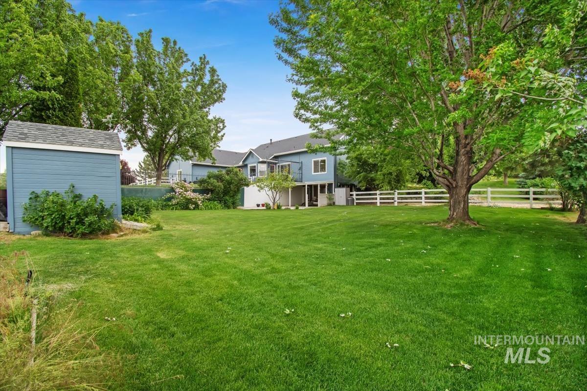 10462 West Lanktree Gulch Road Star, ID 83669 - Photo 45 of 48 Expansive green lawn with mature trees, a blue detached shed, and a privacy fence