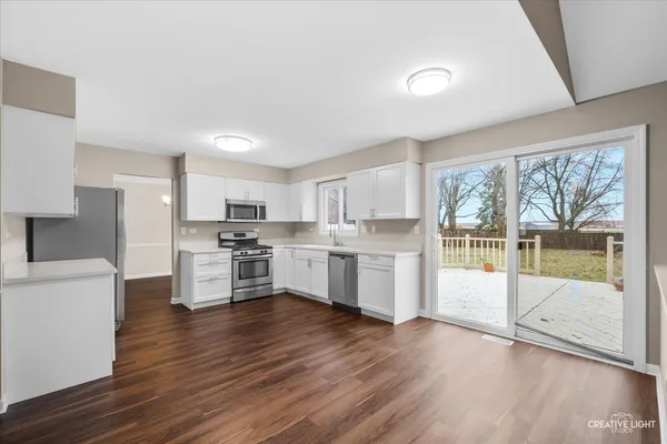 a kitchen with white cabinets and wooden floor