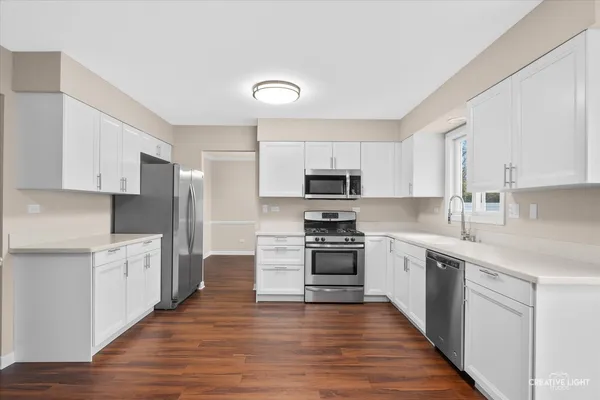 a large kitchen with stainless steel appliances and white cabinets