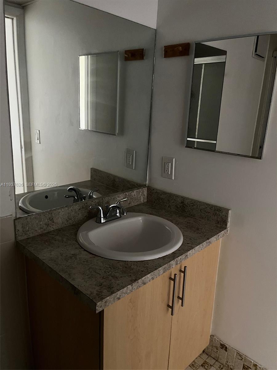 8420 Southwest 133rd Avenue Road, Unit 308 Miami, FL 33183 - Photo 15 of 16 a bathroom with a granite countertop sink and a mirror