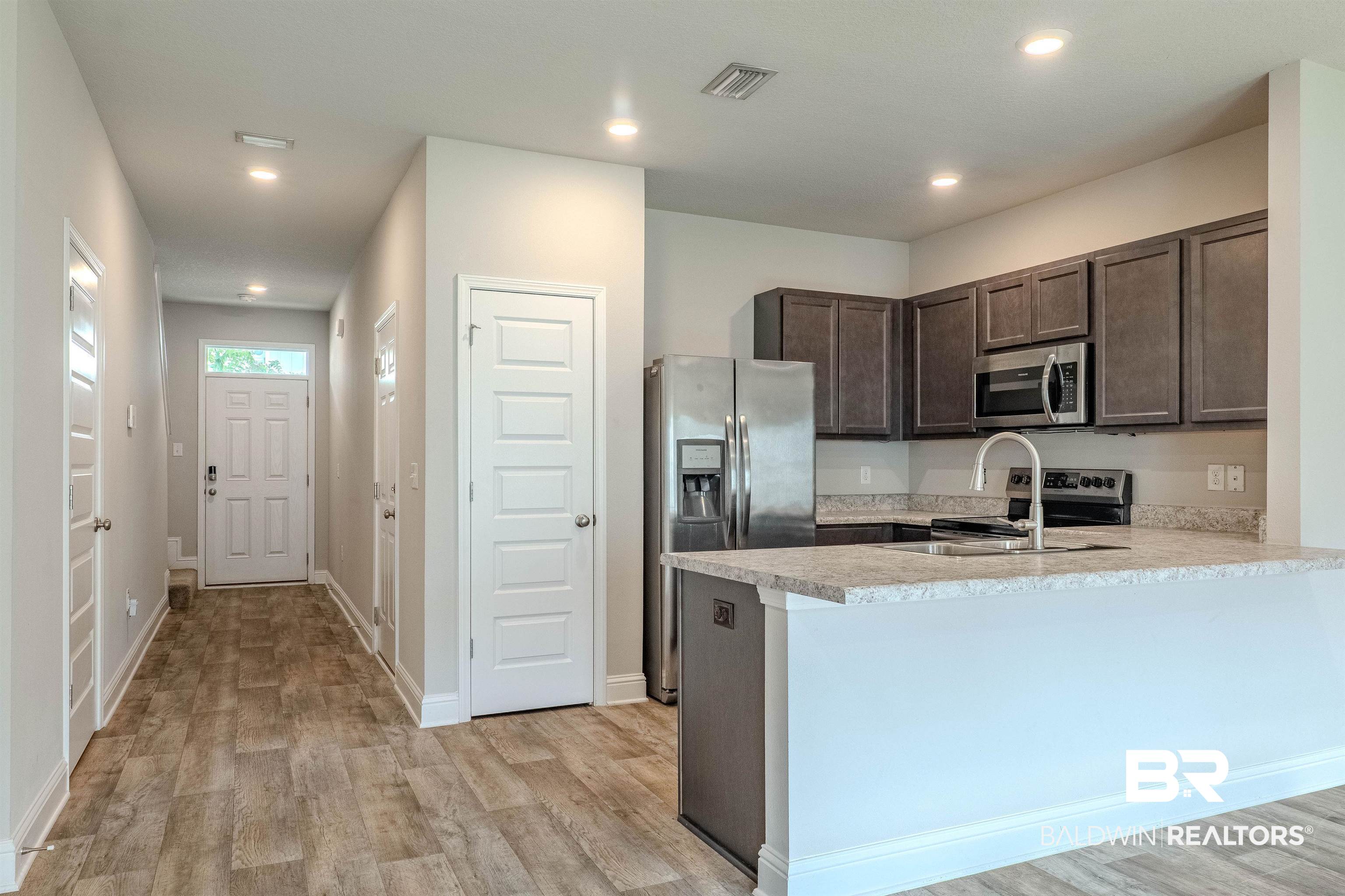 25806 Pollard Road, Unit 32 Daphne, AL 36526 - Photo 3 of 23 Kitchen featuring light hardwood / wood-style floors, sink, kitchen peninsula, stainless steel appliances, and dark brown cabinetry