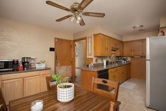 a kitchen with a refrigerator a sink dishwasher a dining table and chairs with wooden floor