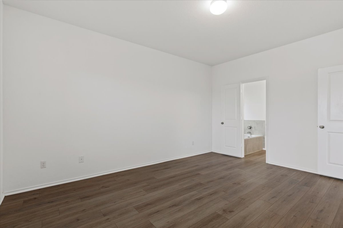 101 Rowdy Yates Way Jarrell, TX 76537 - Photo 15 of 32 Spacious room featuring wood-finish flooring, white baseboards, and bright white walls