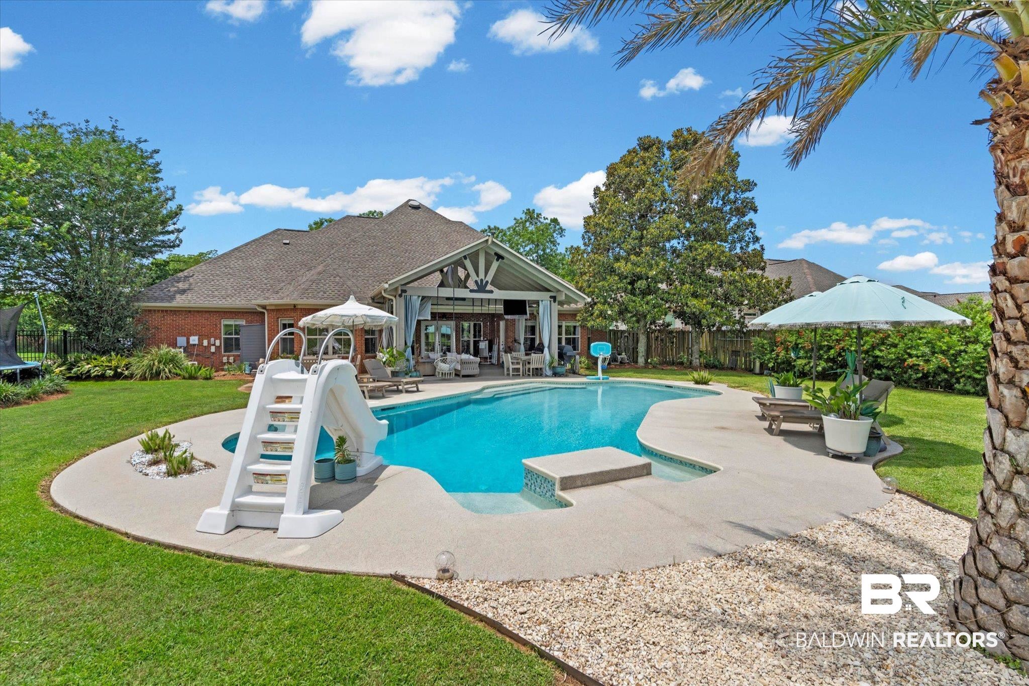 24908 Bosbyshell Avenue Daphne, AL 36526 - Photo 30 of 49 Curved inground pool with integrated steps, surrounded by a concrete patio and manicured lawn